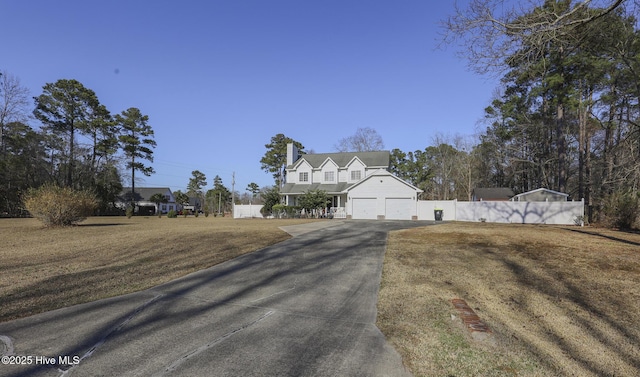 view of front of property with driveway, an attached garage, fence, and a front yard