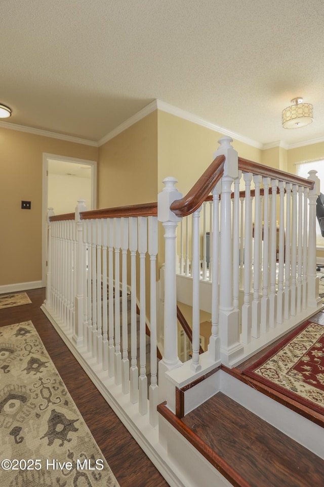 staircase with baseboards, a textured ceiling, ornamental molding, and wood finished floors