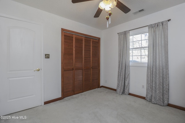 unfurnished bedroom featuring a textured ceiling, a closet, carpet flooring, and visible vents