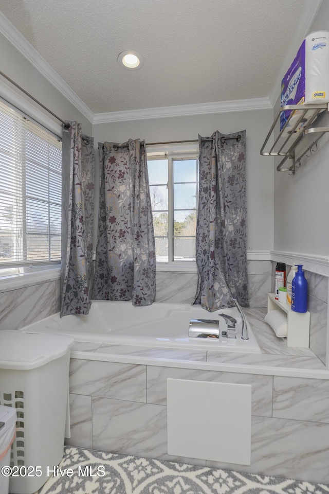 full bath featuring ornamental molding, a healthy amount of sunlight, a garden tub, and a textured ceiling