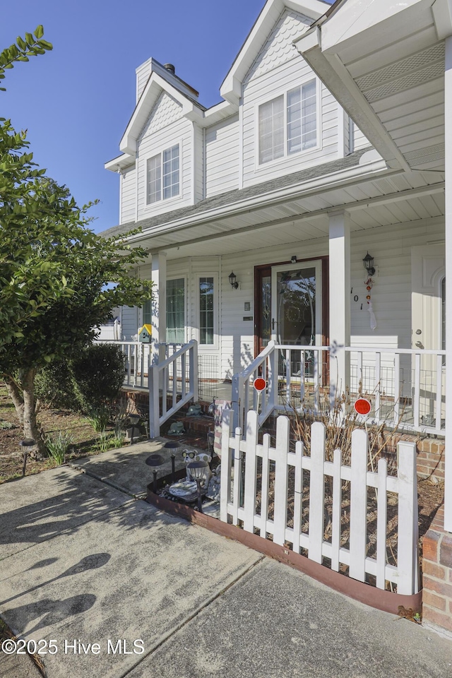 townhome / multi-family property featuring covered porch and a fenced front yard