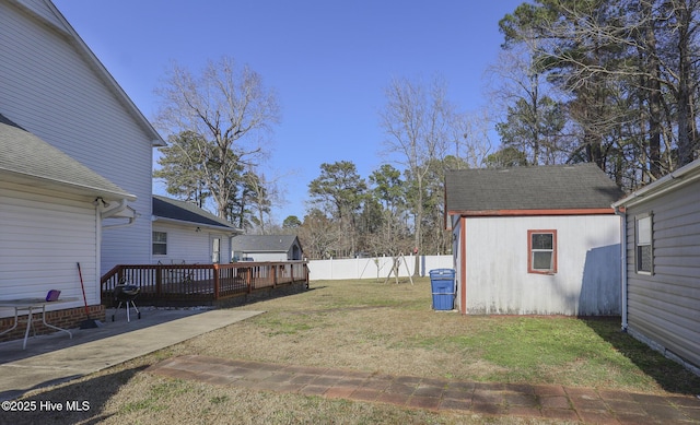 view of yard featuring an outdoor structure, a deck, and fence