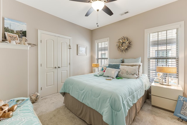 bedroom with light carpet, a closet, visible vents, and a ceiling fan