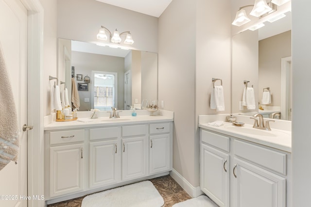 full bathroom with baseboards, two vanities, and a sink