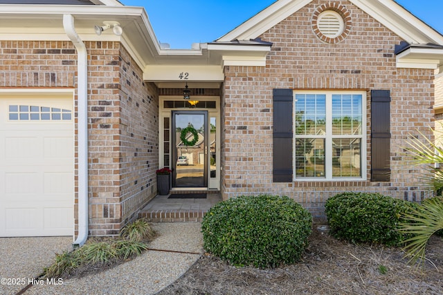 entrance to property with brick siding and an attached garage