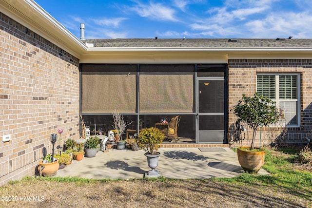 exterior space with a sunroom, a patio area, and brick siding