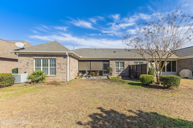 rear view of property featuring a yard, brick siding, cooling unit, and fence