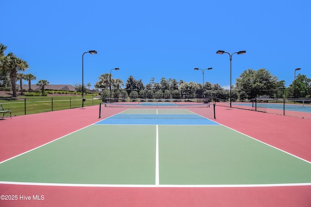 view of tennis court featuring community basketball court and fence