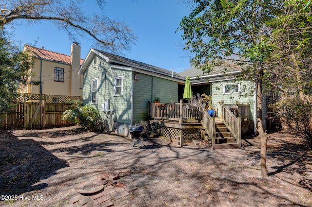 back of property featuring fence, a chimney, and a wooden deck