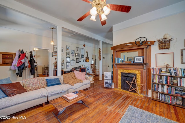 living area with a fireplace, a ceiling fan, and hardwood / wood-style floors