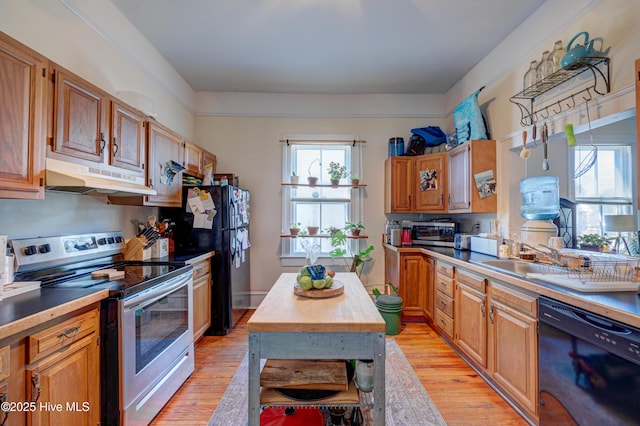 kitchen with black appliances, light wood-style floors, a healthy amount of sunlight, and under cabinet range hood