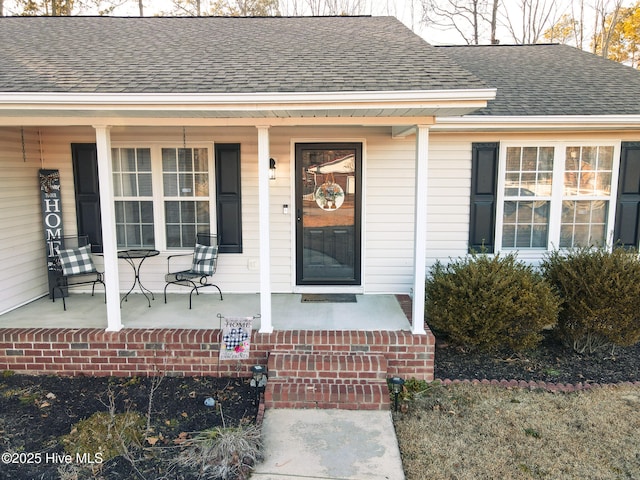 entrance to property featuring covered porch and roof with shingles