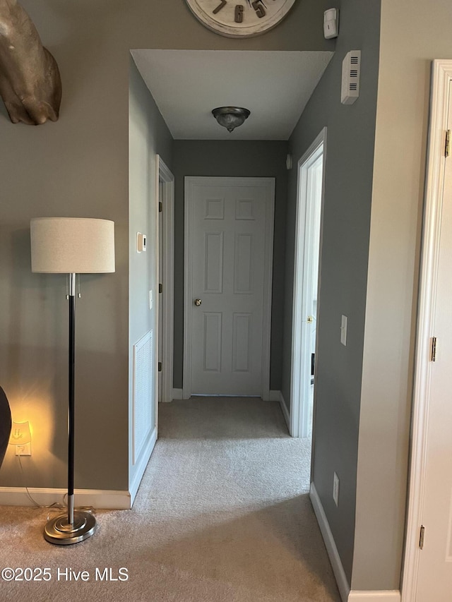 corridor featuring light colored carpet and baseboards