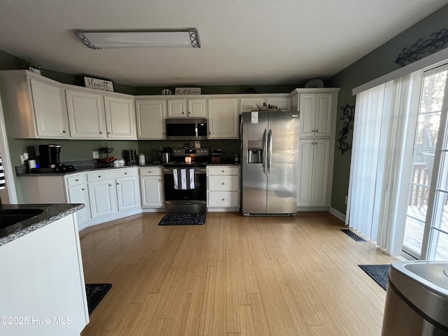 kitchen featuring appliances with stainless steel finishes, light wood-type flooring, and white cabinets