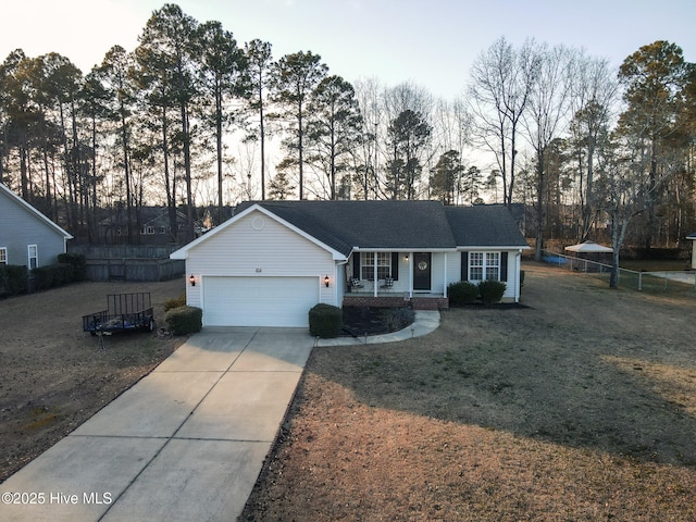 ranch-style house featuring an attached garage, covered porch, fence, concrete driveway, and a front yard