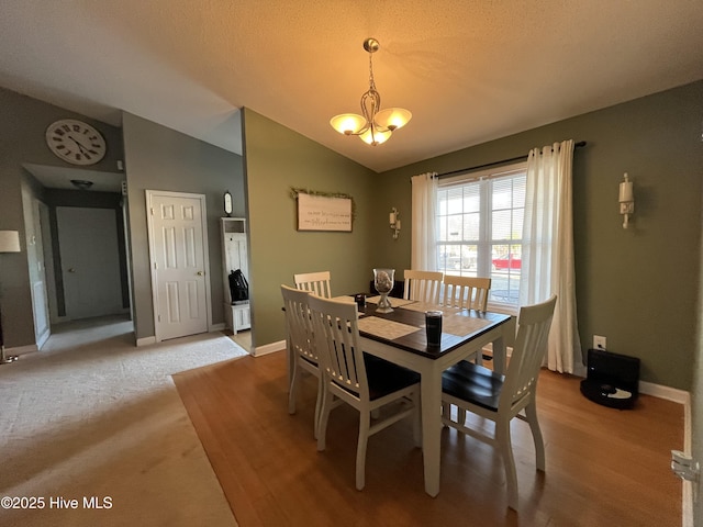 dining area featuring lofted ceiling, a textured ceiling, baseboards, and a notable chandelier