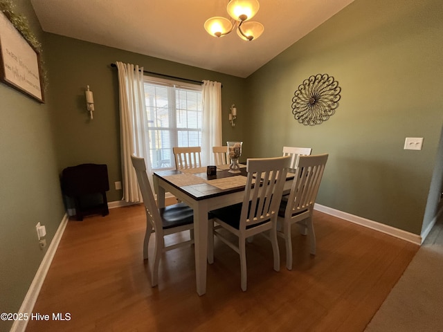 dining space with baseboards, vaulted ceiling, and wood finished floors