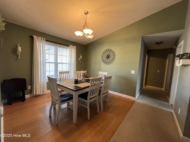 dining area with vaulted ceiling, light wood finished floors, an inviting chandelier, and baseboards