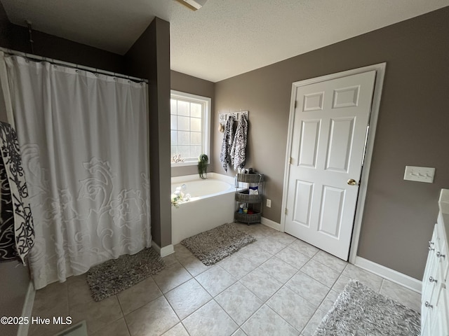 bathroom featuring a garden tub, a textured ceiling, tile patterned flooring, and baseboards