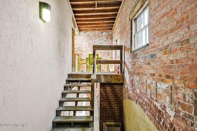 staircase featuring brick wall