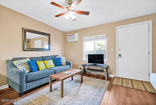 living area with a ceiling fan, baseboards, wood finished floors, and a wall mounted AC