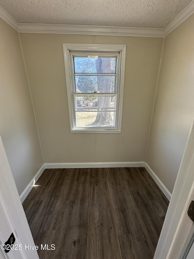 empty room with dark wood-style floors, crown molding, a textured ceiling, and baseboards