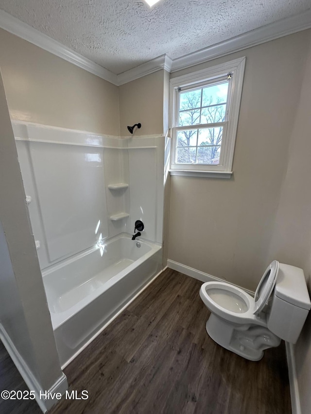 full bath with a textured ceiling, bathtub / shower combination, toilet, wood finished floors, and crown molding