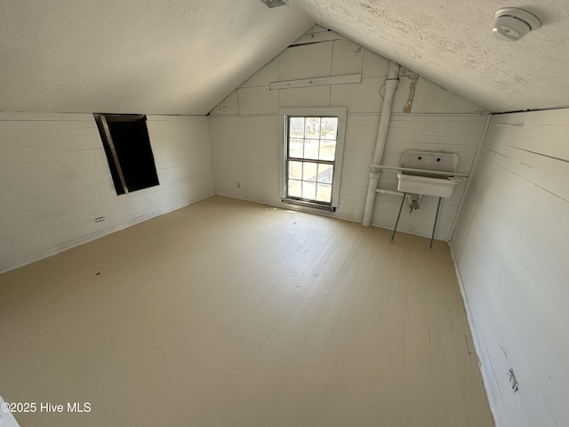 bonus room with lofted ceiling, a textured ceiling, and hardwood / wood-style floors