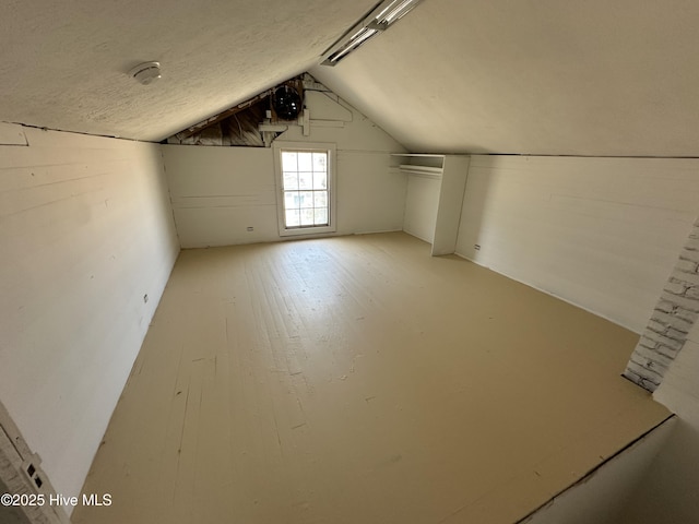 additional living space with lofted ceiling, light wood finished floors, and a textured ceiling