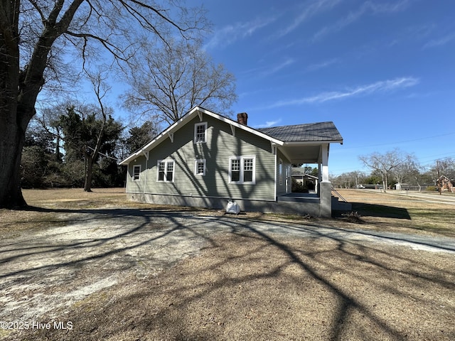 view of front of home with driveway, covered porch, and a chimney