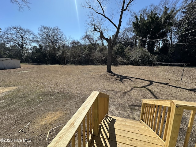 view of yard featuring a wooden deck and a storage unit