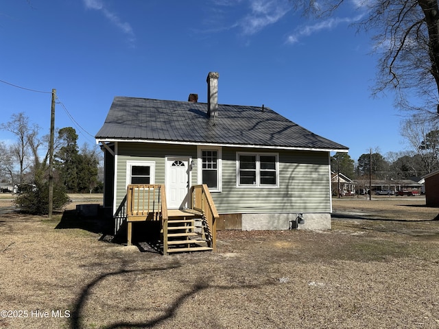 rear view of house featuring a chimney and metal roof