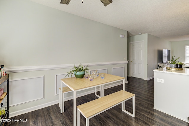 dining space featuring a ceiling fan, dark wood-style flooring, a wainscoted wall, and a textured ceiling