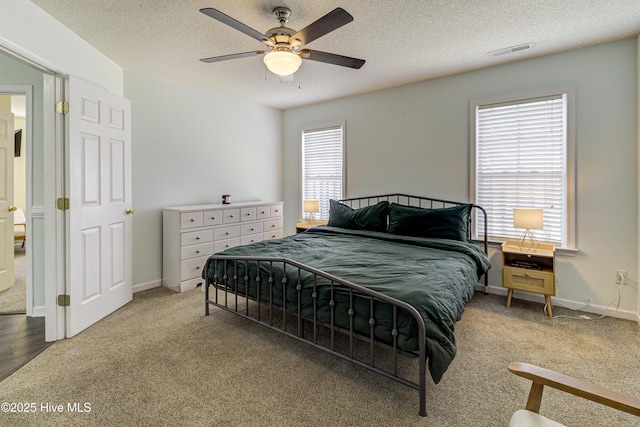 bedroom with carpet floors, baseboards, visible vents, and a textured ceiling