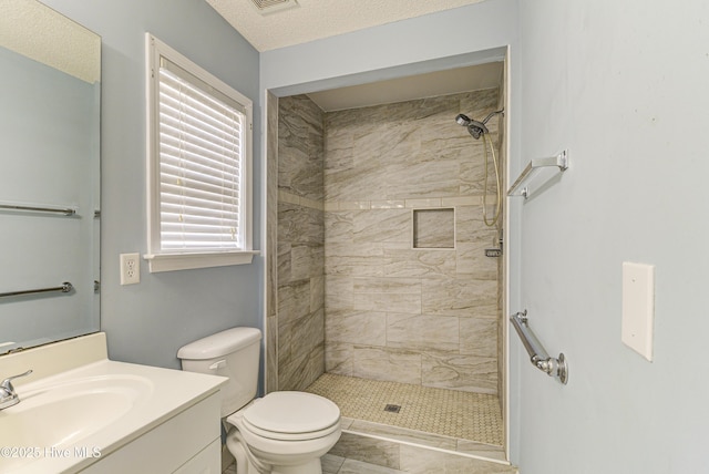 full bathroom with visible vents, tiled shower, toilet, a textured ceiling, and vanity