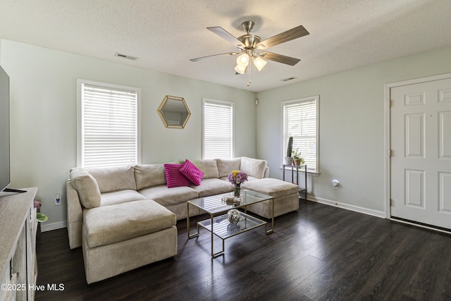 living area with a ceiling fan, visible vents, and dark wood-type flooring