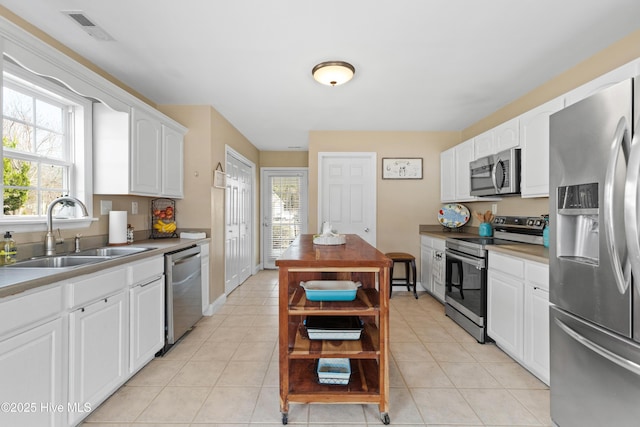 kitchen featuring appliances with stainless steel finishes, visible vents, a sink, and light tile patterned floors