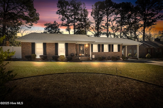 ranch-style house featuring a yard, crawl space, brick siding, and fence