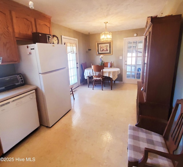 kitchen with white appliances, a toaster, brown cabinets, hanging light fixtures, and light countertops