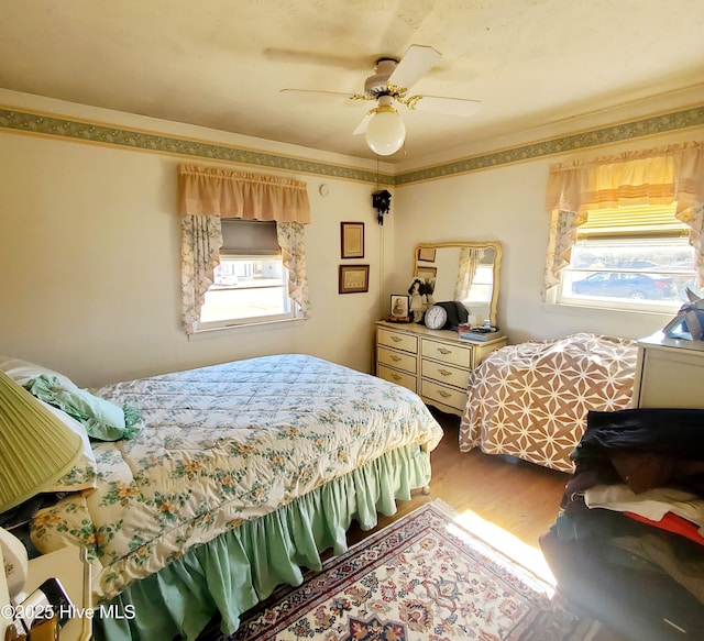 bedroom featuring a ceiling fan, crown molding, and wood finished floors