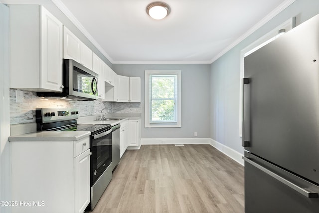 kitchen with light countertops, appliances with stainless steel finishes, white cabinetry, and crown molding