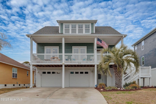 coastal inspired home with a shingled roof, concrete driveway, and a garage