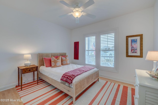 bedroom with baseboards, light wood-type flooring, and a ceiling fan