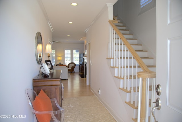 corridor featuring ornamental molding, recessed lighting, light wood-style floors, baseboards, and stairs