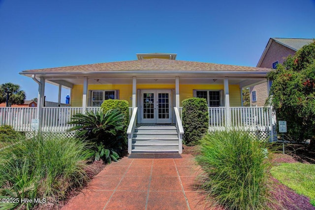 bungalow featuring a porch, french doors, and a shingled roof