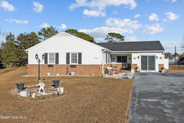 single story home featuring driveway, brick siding, a front lawn, and an attached garage