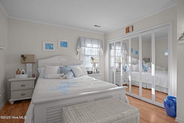 bedroom with ornamental molding, wood finished floors, and visible vents