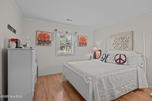 bedroom with baseboards, visible vents, crown molding, and light wood finished floors