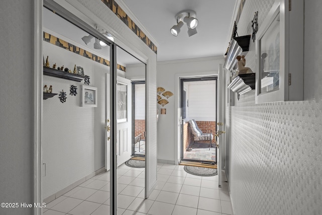 entryway with light tile patterned floors, ornamental molding, and baseboards