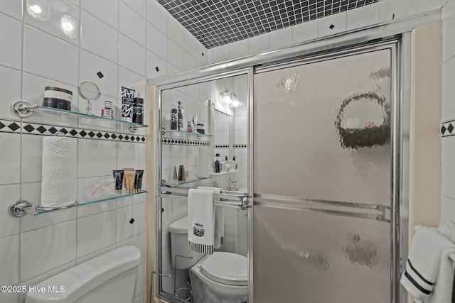 bathroom featuring tile walls, a shower stall, and toilet